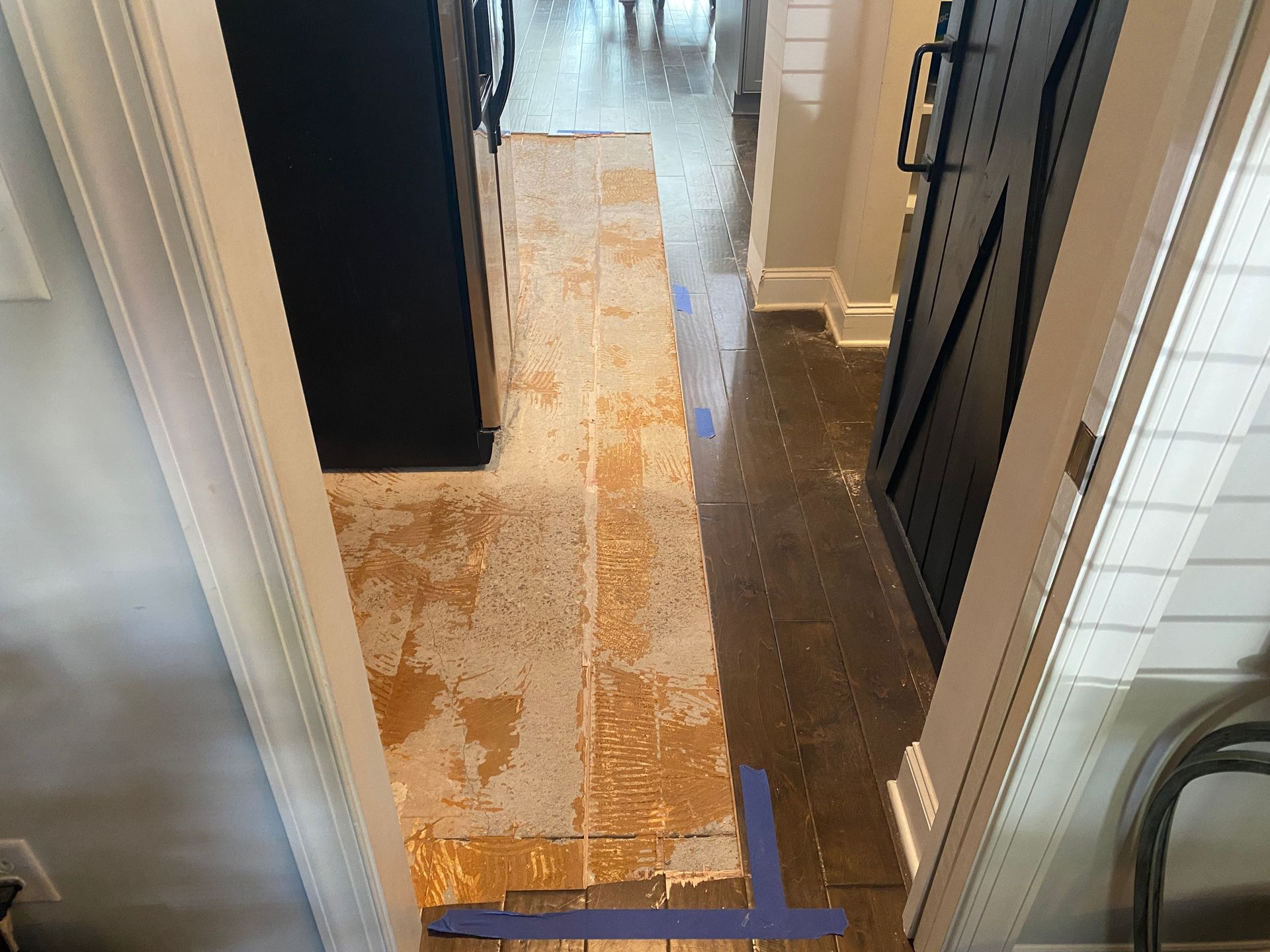 A hallway in a house with a blue tape on the floor.