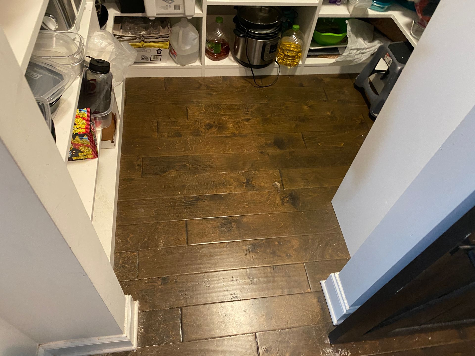 A pantry with a wooden floor and white shelves