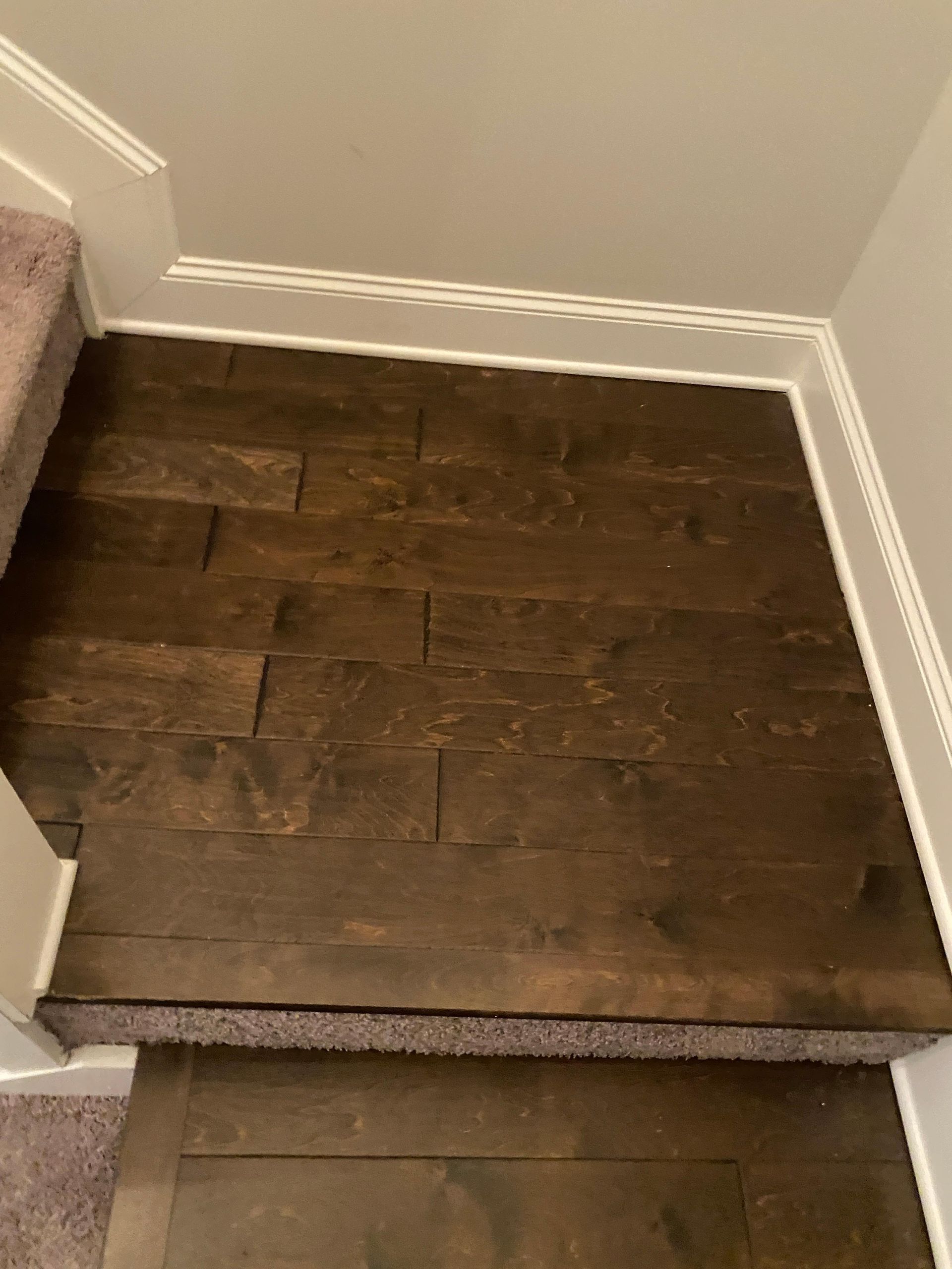 A wooden floor next to a set of stairs in a house.
