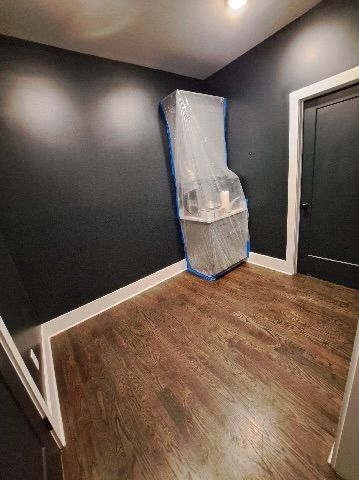 A room with black walls and hardwood floors is being painted.