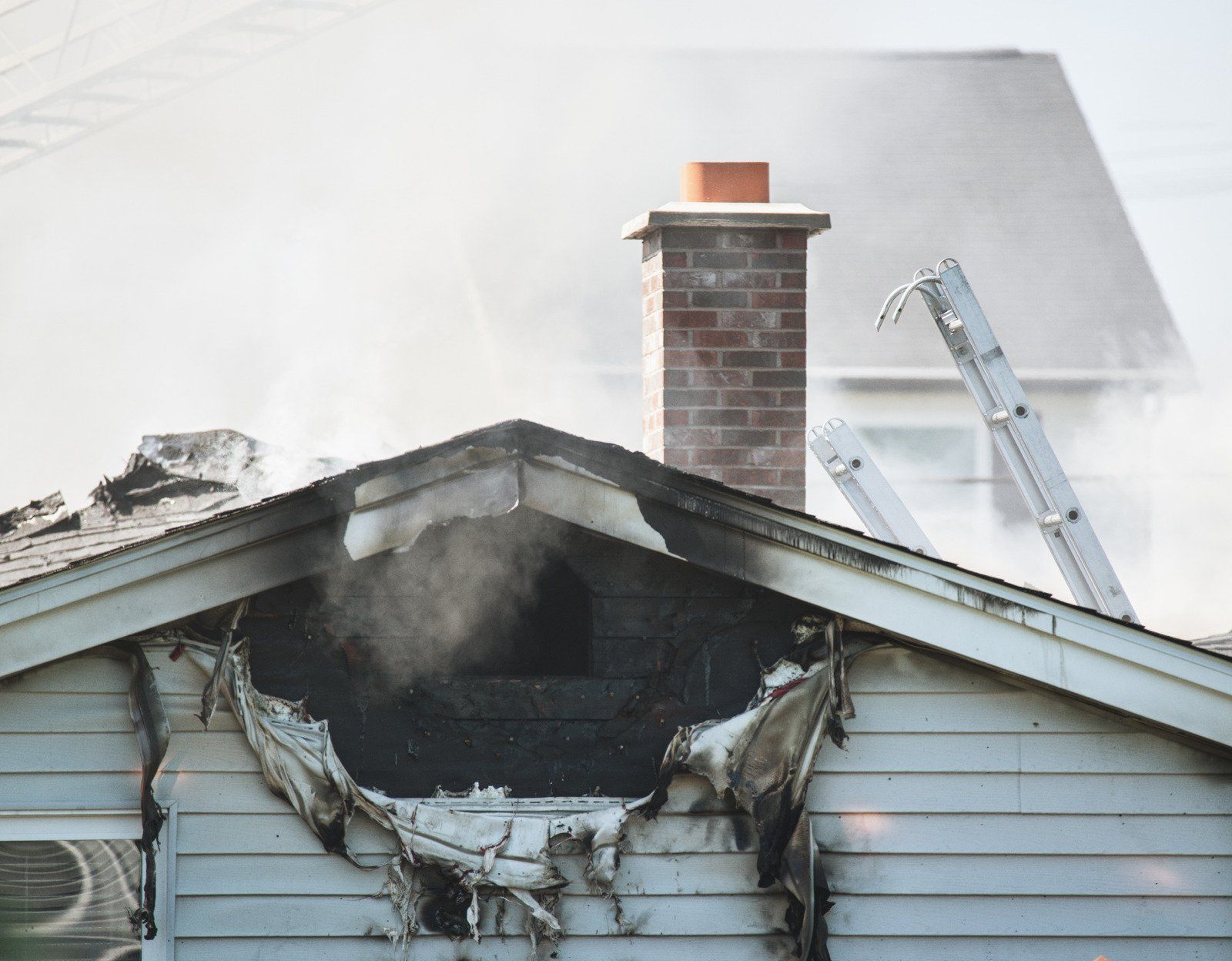 A house that has been damaged by a fire with smoke coming out of the chimney.