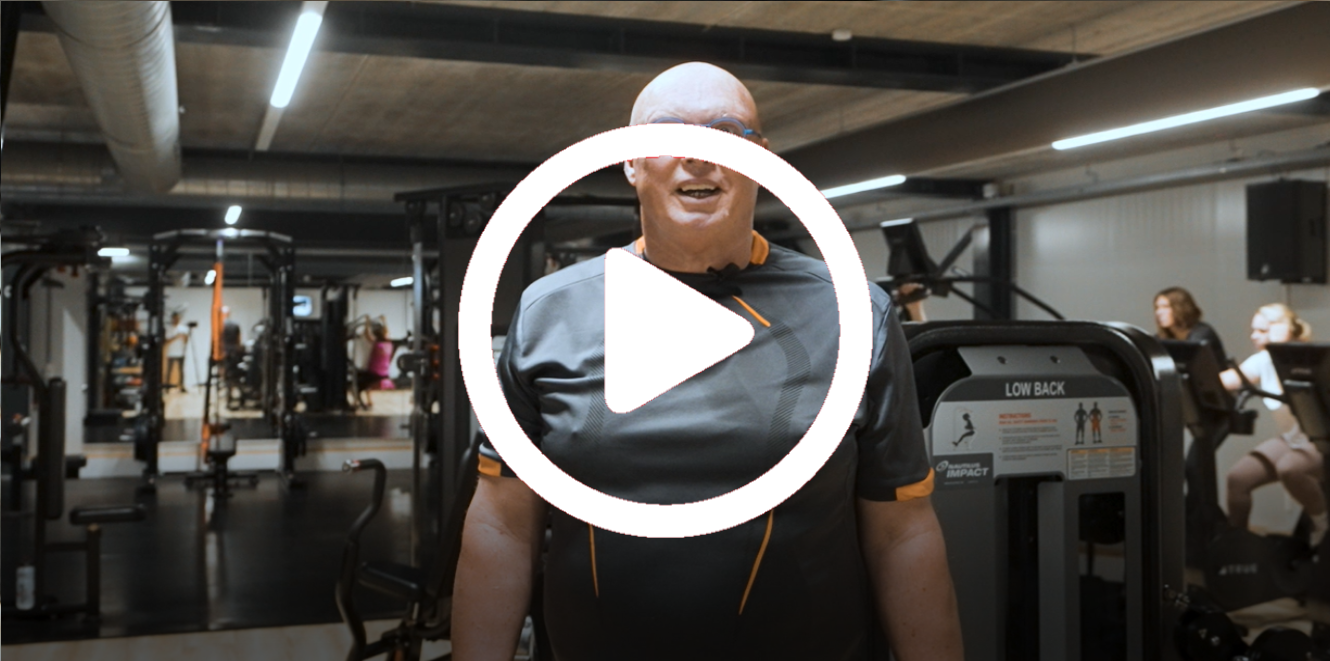 Een man in een sportschool lacht naar de camera, met daaroverheen een afspeelknop. 