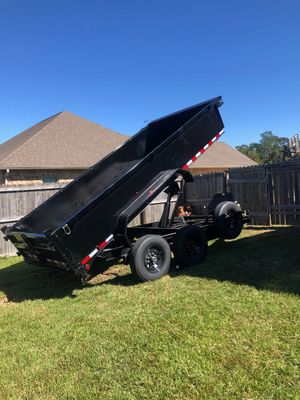 A dump truck is parked in the grass in front of a house.