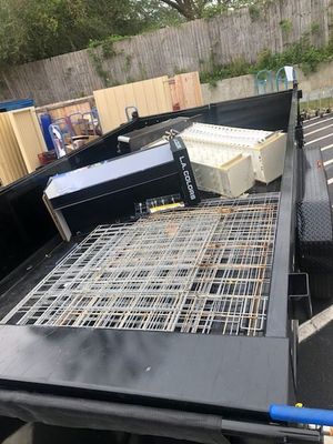 A black truck with a metal grid on the back is parked in a parking lot.