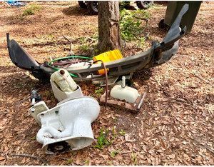 A pile of trash is laying on the ground next to a tree.