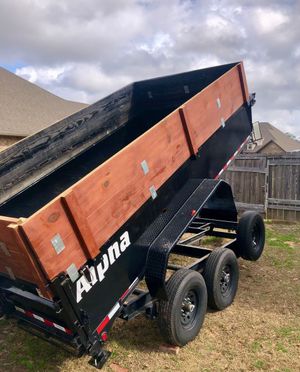 A dump trailer with a wooden bed is parked in a yard.