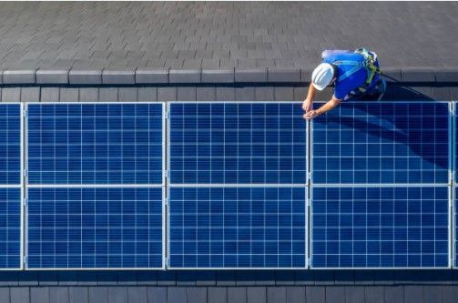 A man installing a solar panel on a roof, providing solar energy solutions.