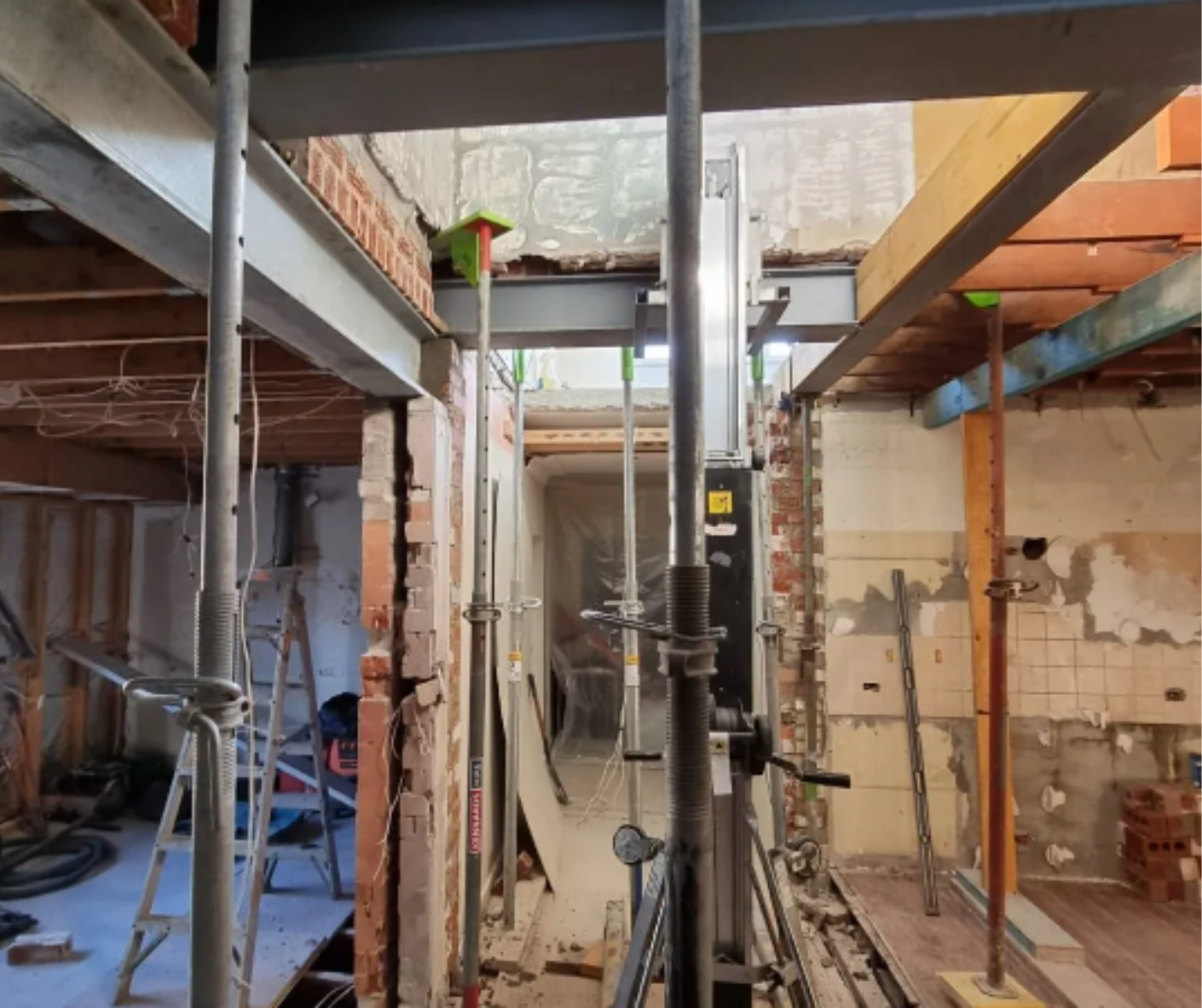 Interior construction site with scaffolding, exposed beams, and work lights in a narrow unfinished room Interior construction site with scaffolding, exposed beams, and work lights in a narrow unfinished room