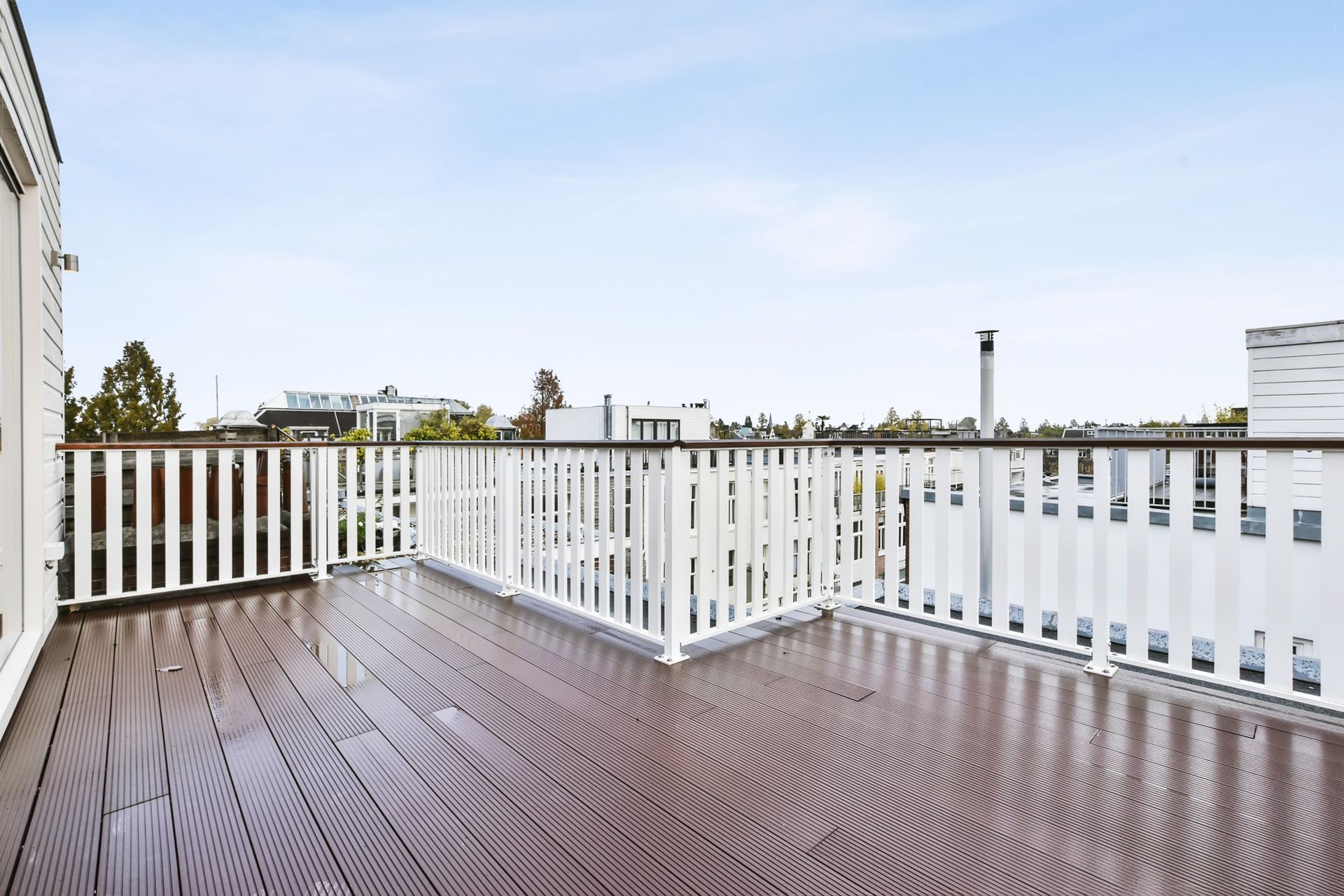 a large wooden deck with a white railing and a blue sky in the background .