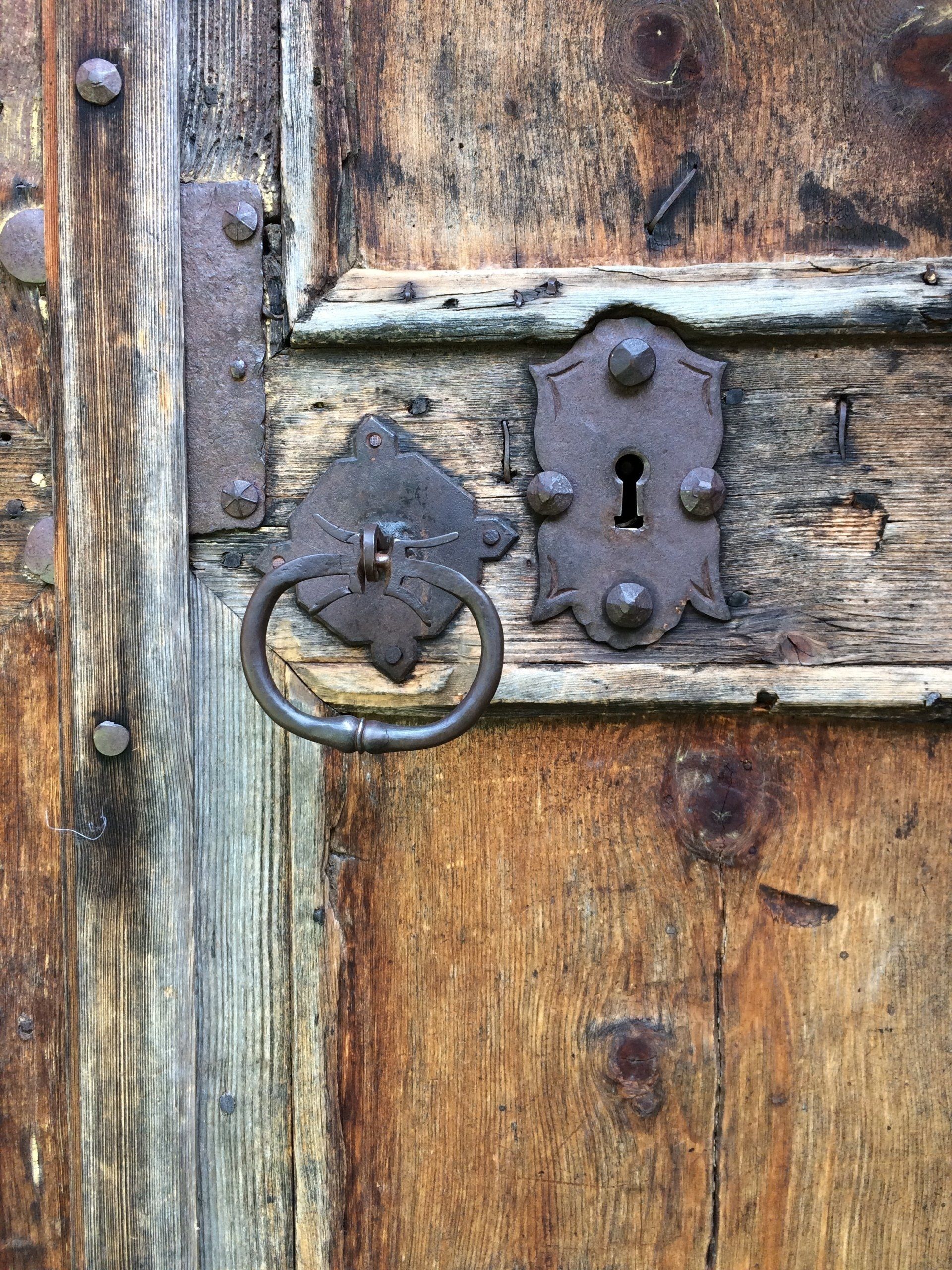 Een close-up van een houten kerkdeur met een sleutelgat en een handvat.