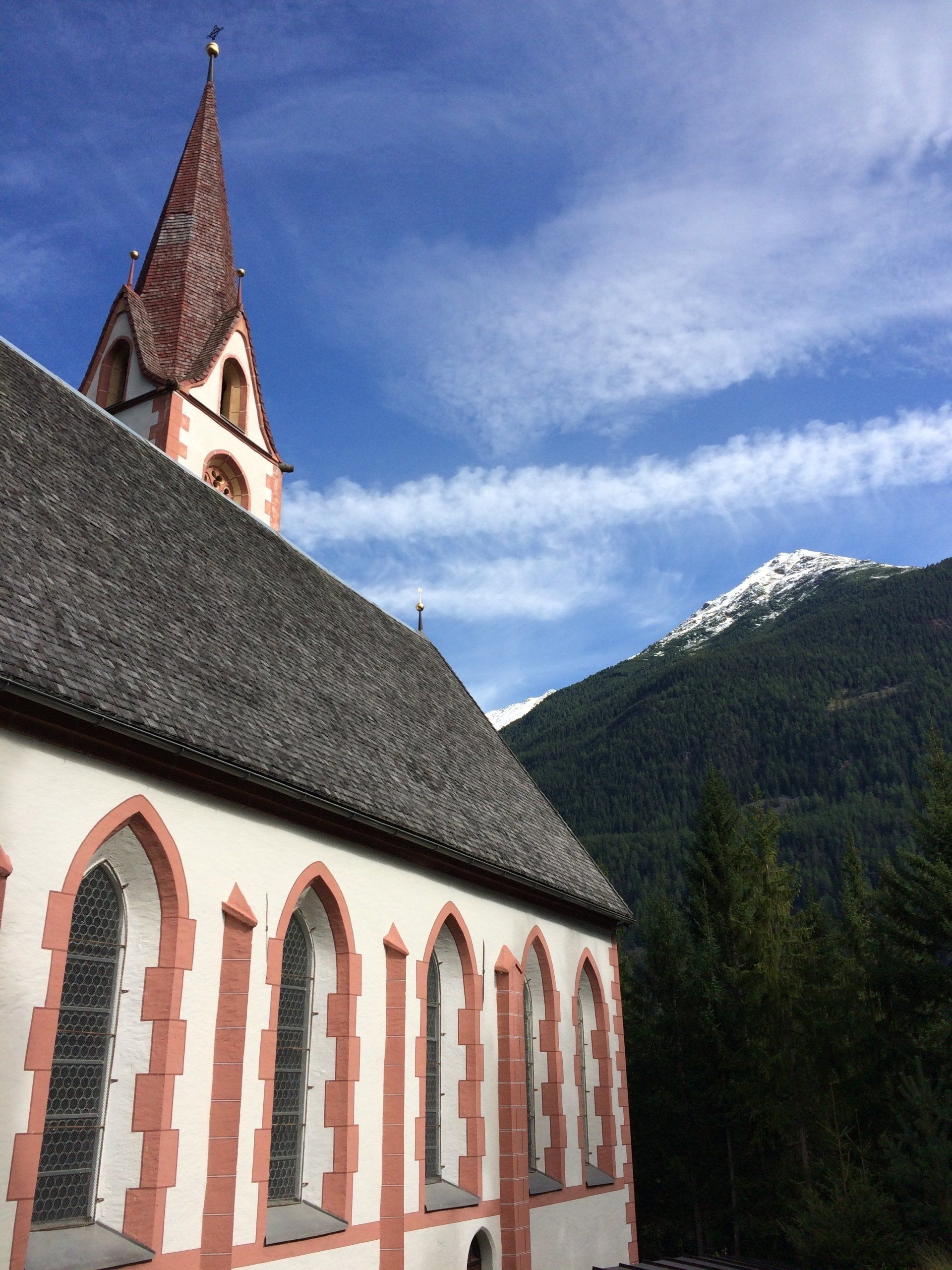 Een kerk met een torenspits en een berg op de achtergrond