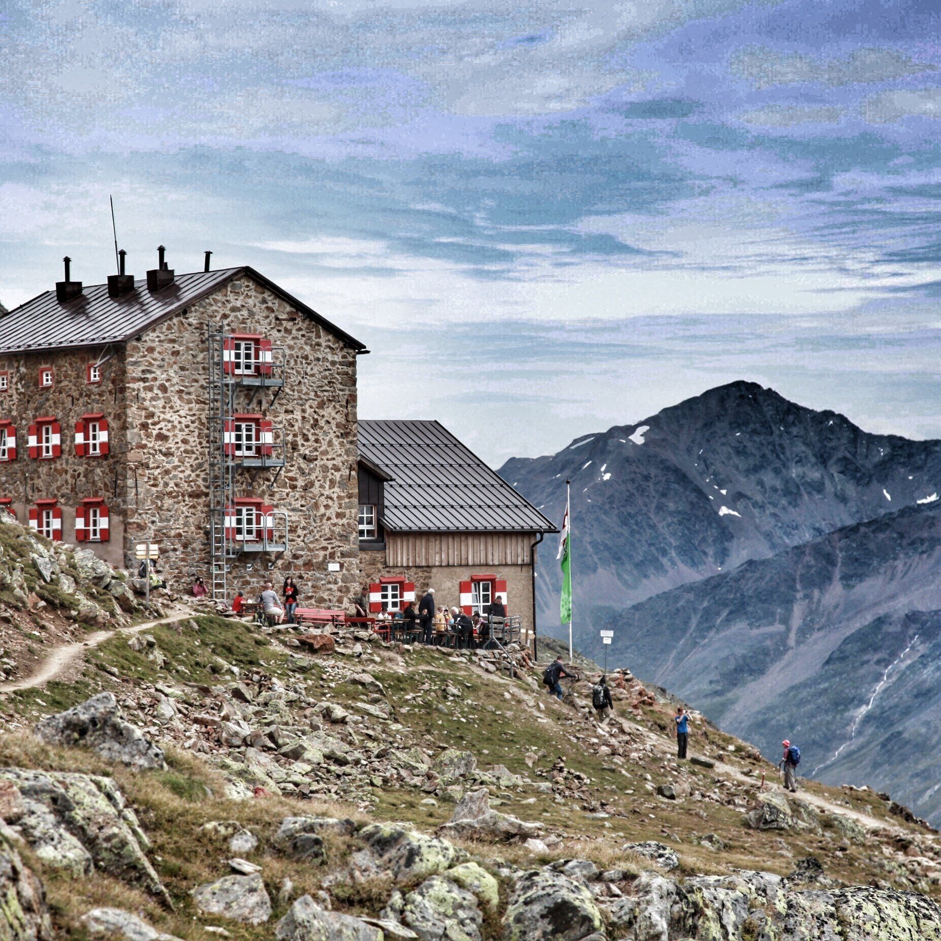 Een berghut op de top van een berg met bergen op de achtergrond