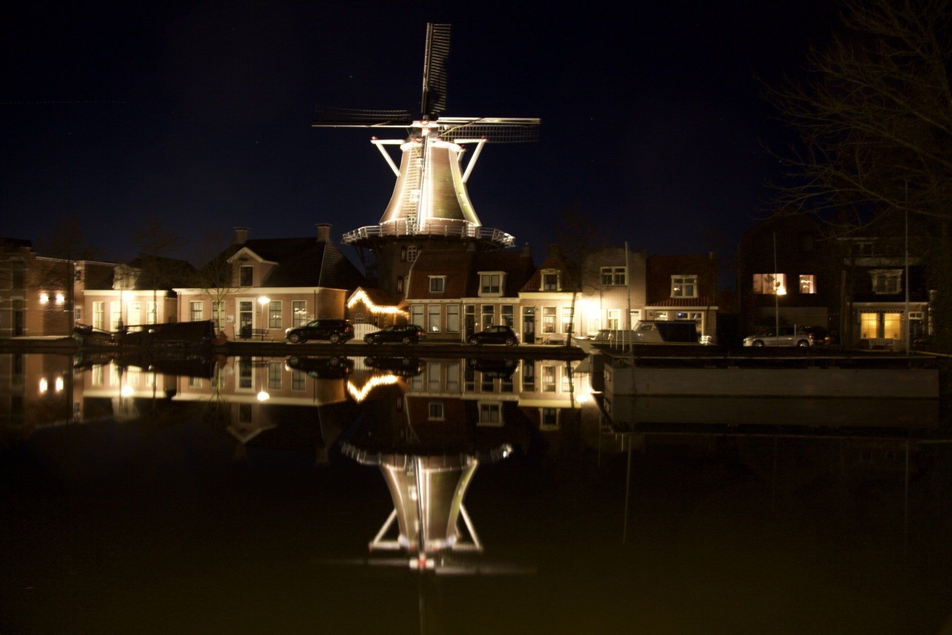 Een molen is 's nachts verlicht en weerspiegelt in het water