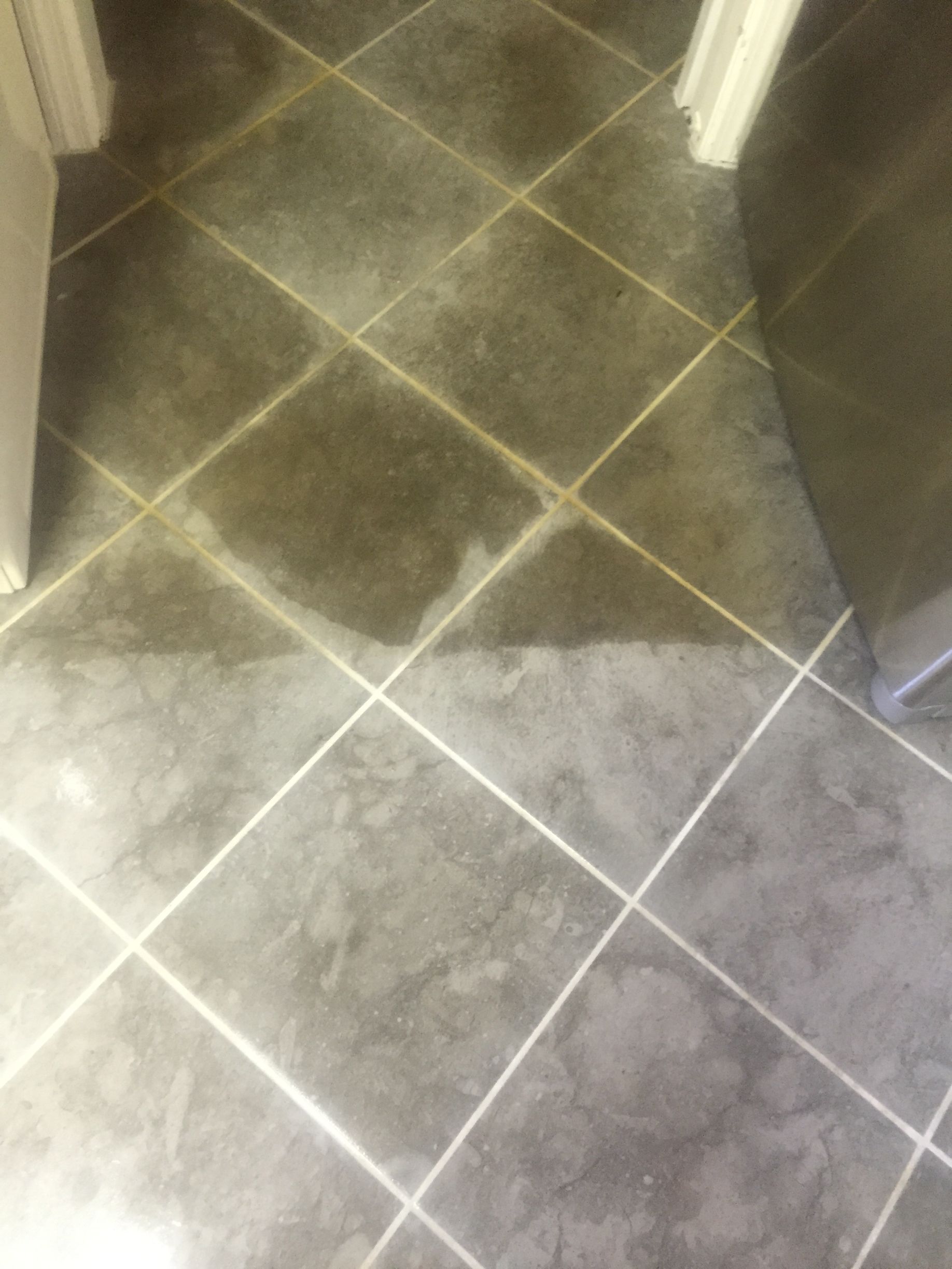 A close up of a tiled floor with a door in the background.