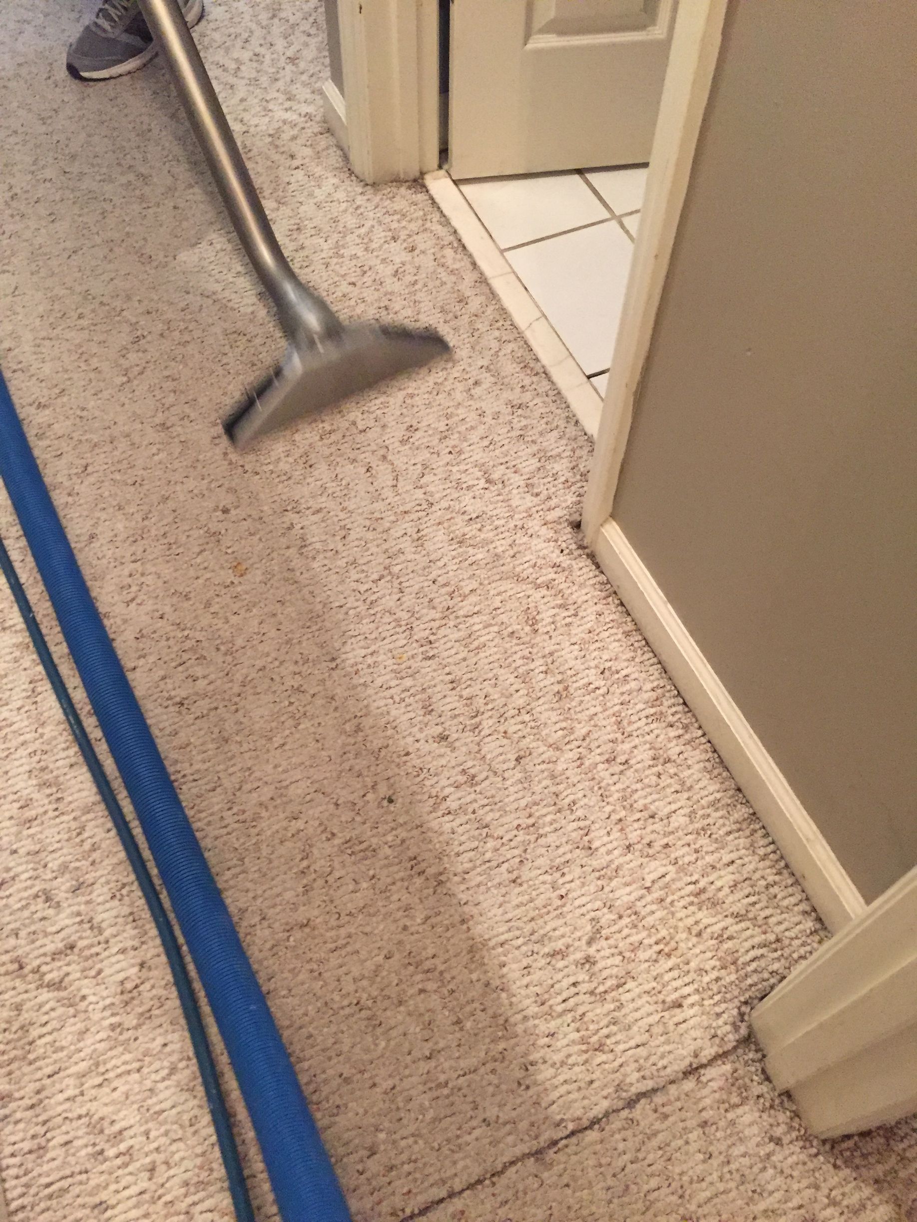 A vacuum cleaner is being used to clean a carpet in a room.