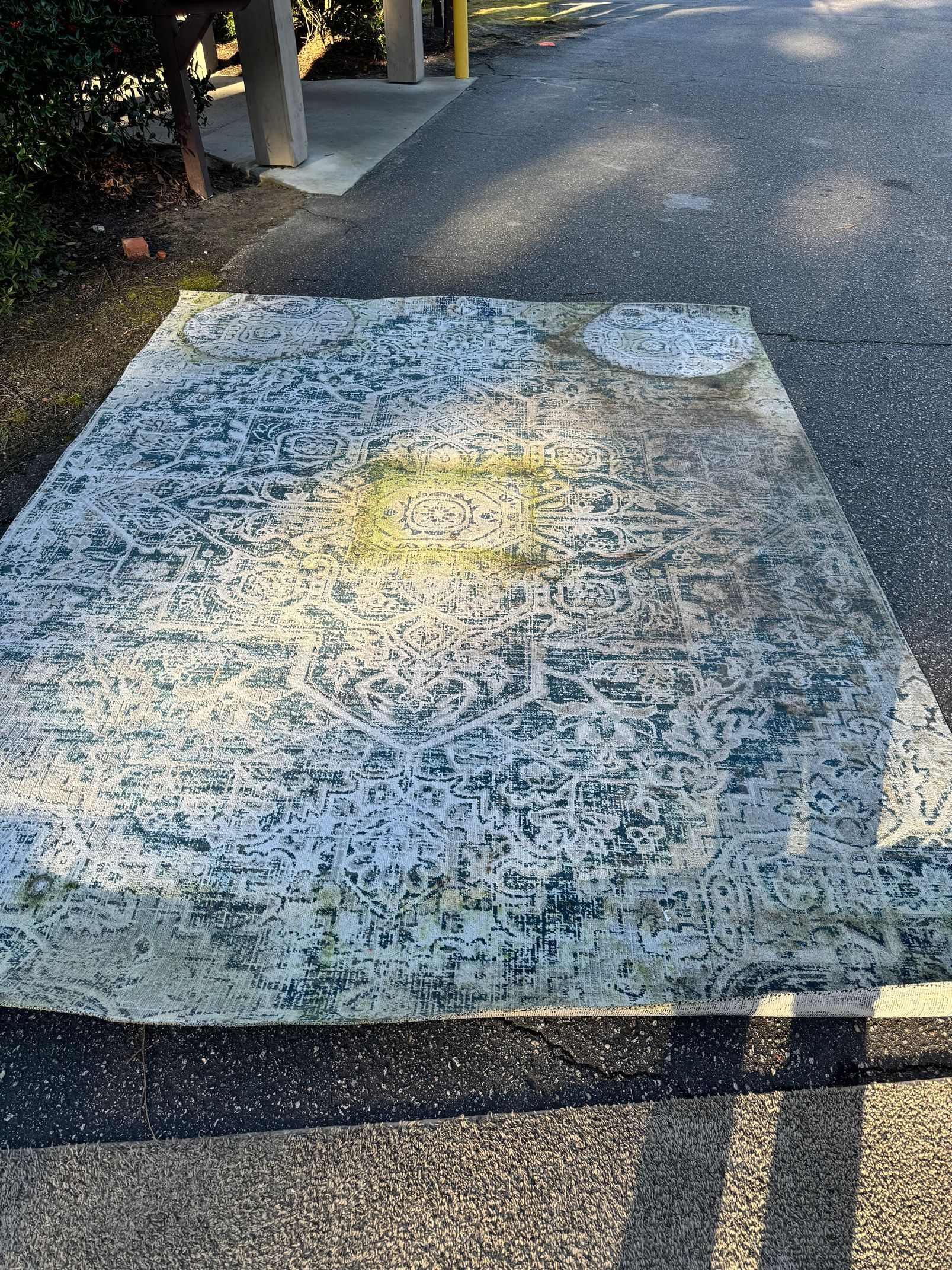 A large rug is sitting on the side of a road.