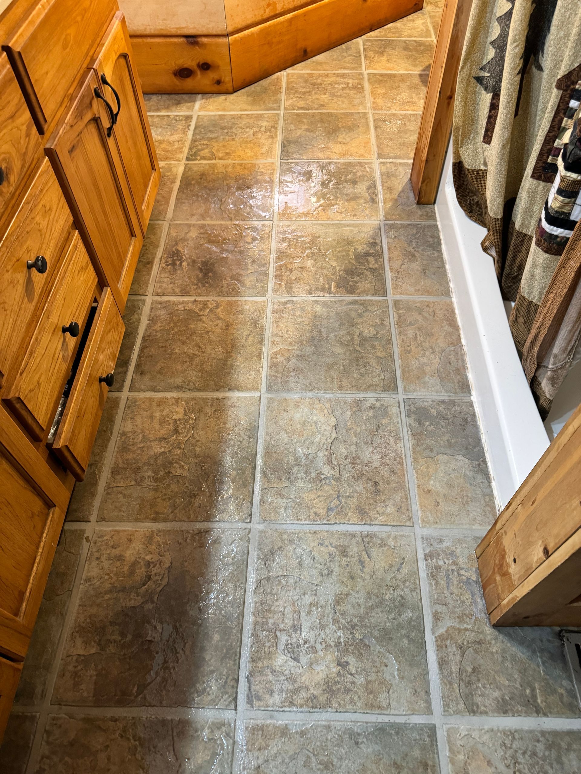 A bathroom with tile floors and wooden cabinets.