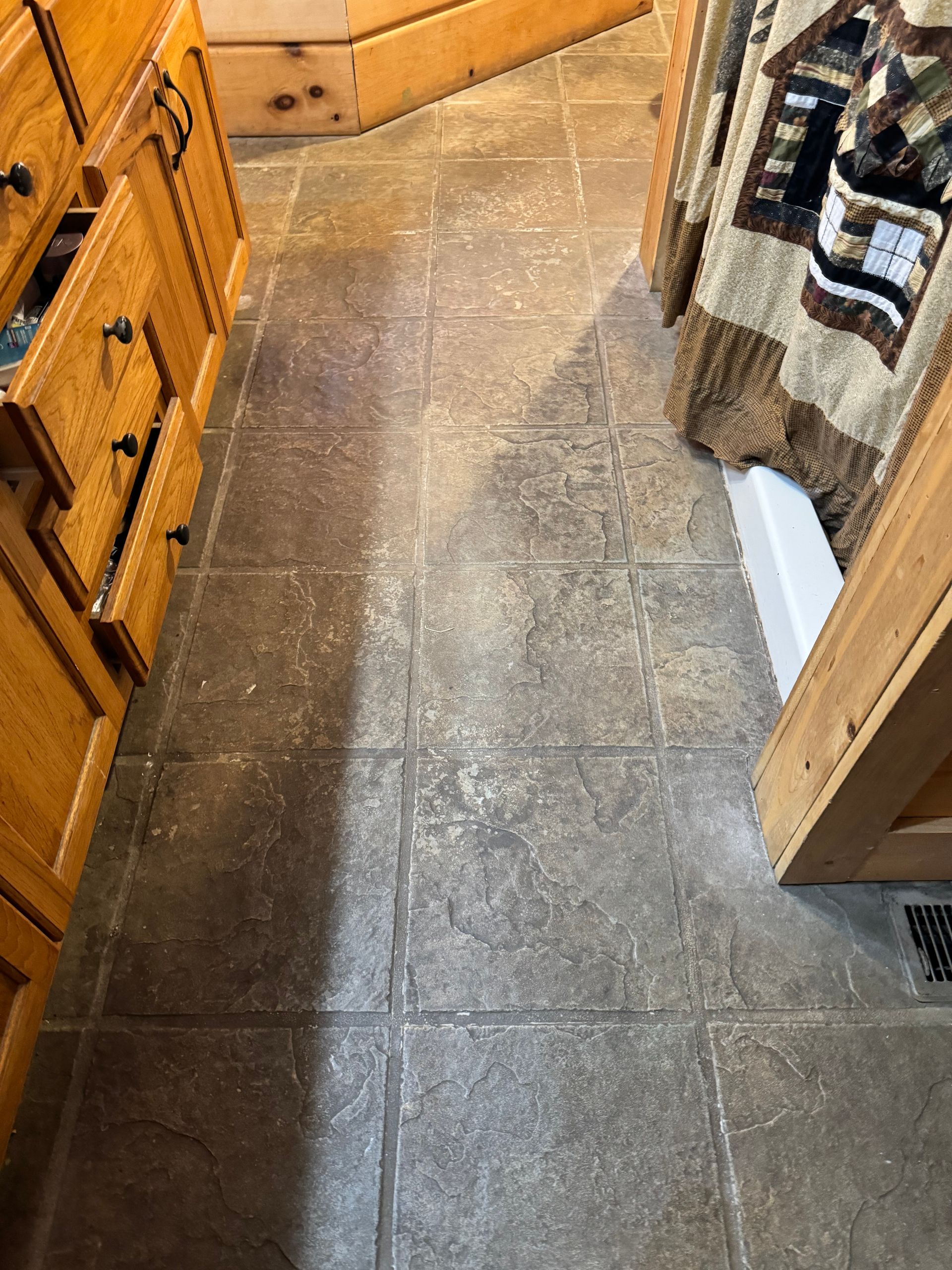 A bathroom with tile floors and wooden cabinets.