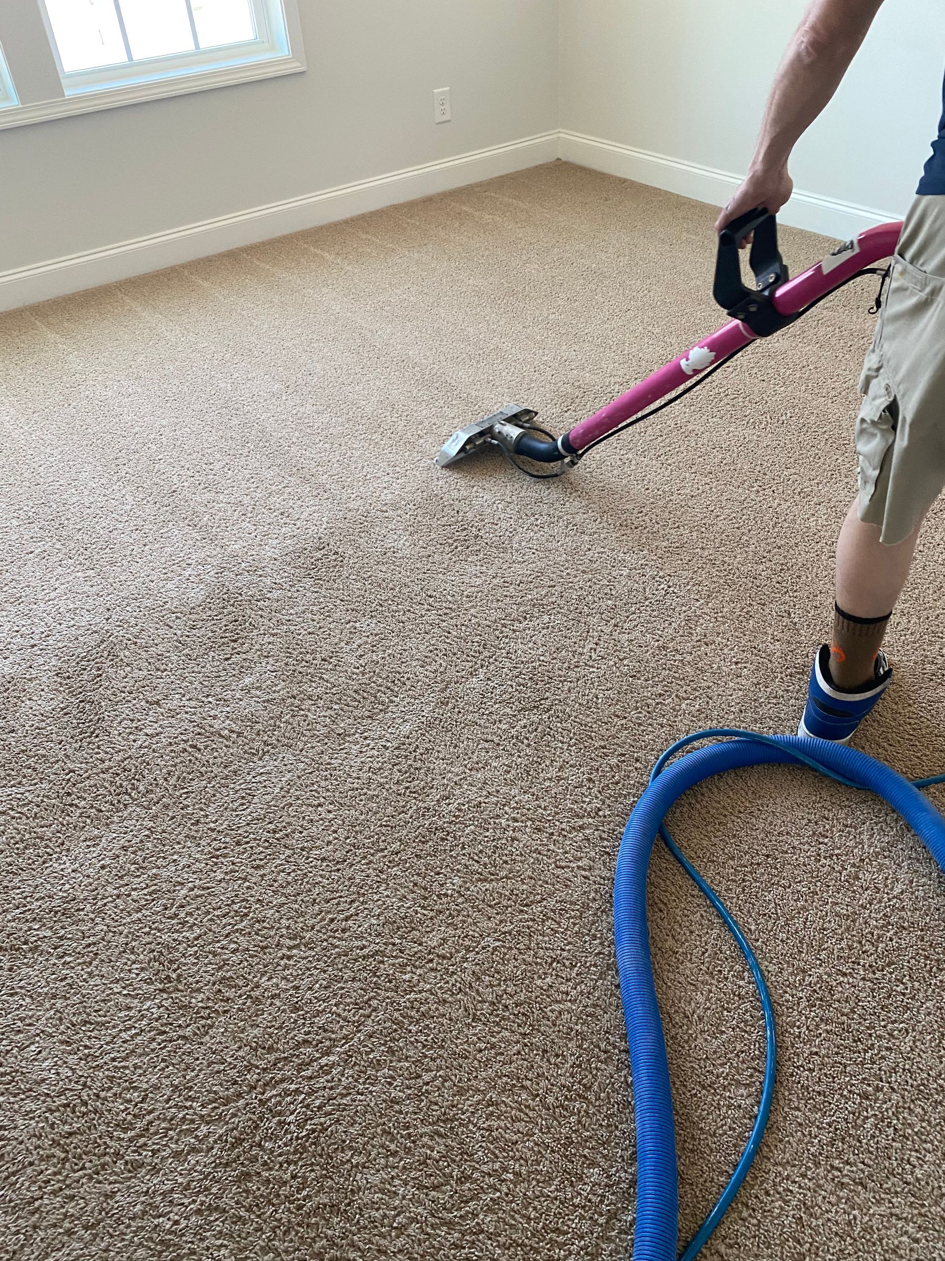 A man is using a vacuum cleaner to clean a carpet in a room.