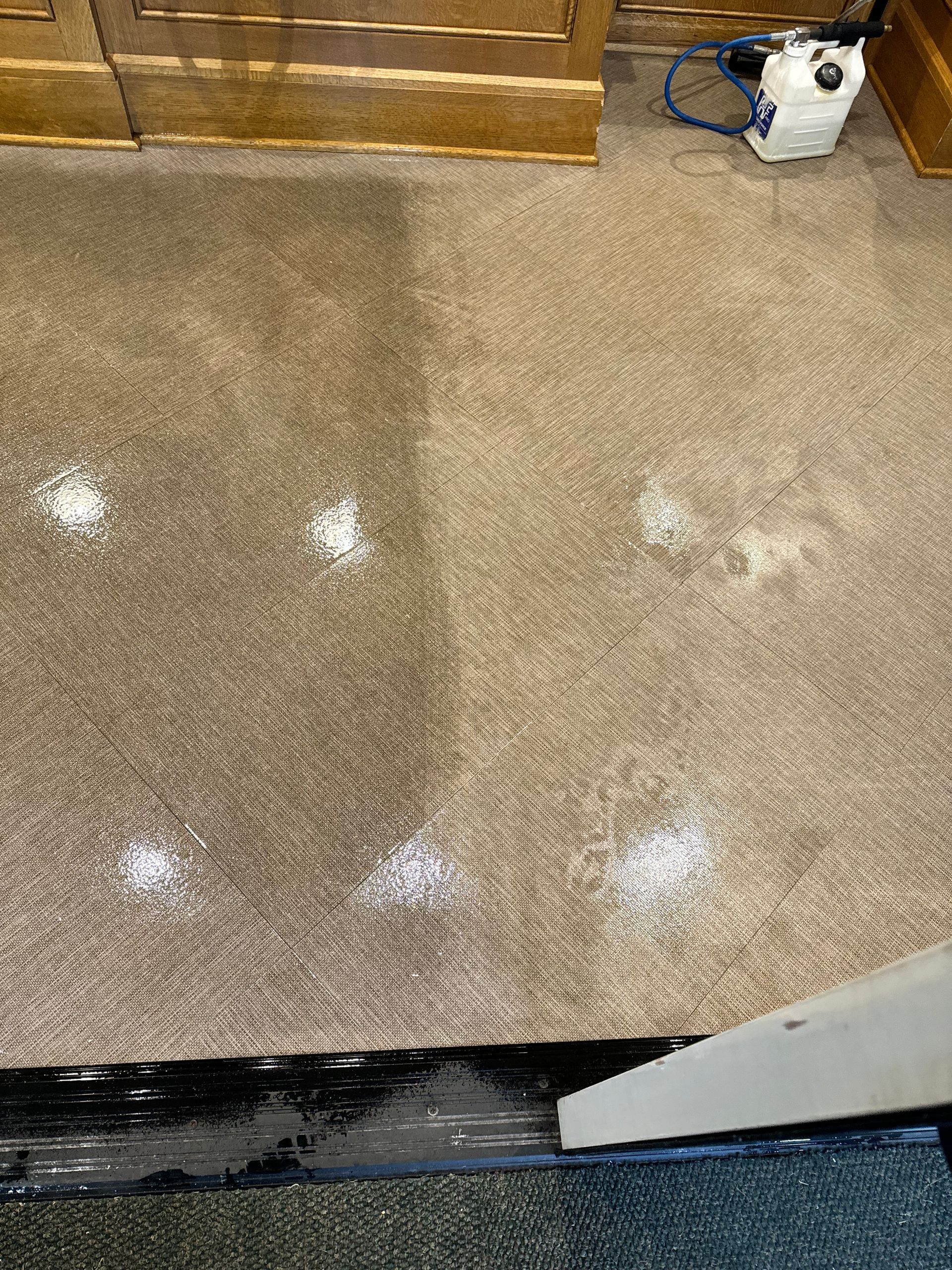 A dirty carpet is being cleaned with a vacuum cleaner.