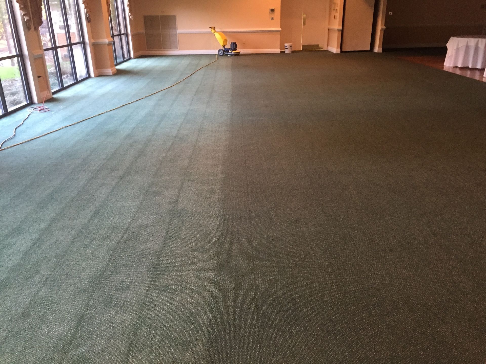 A man is cleaning a carpet in a large room