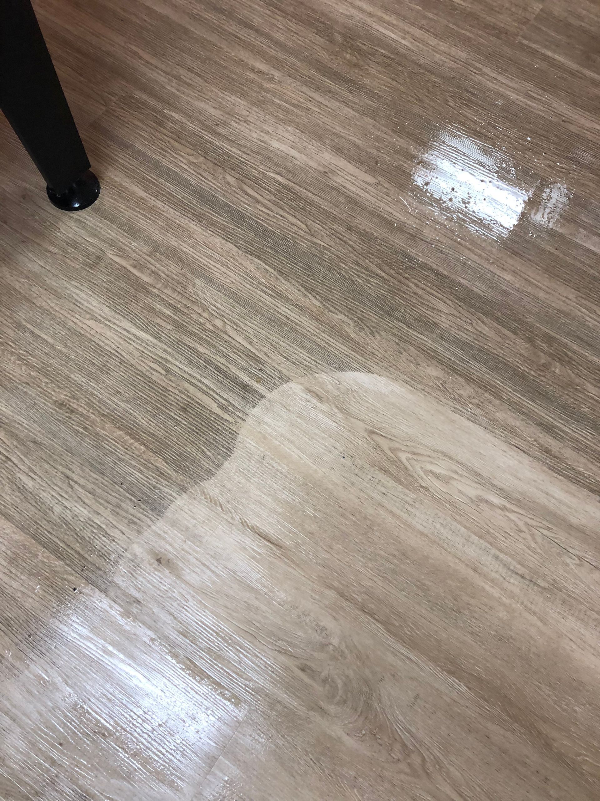 A close up of a wooden floor with a chair in the background.