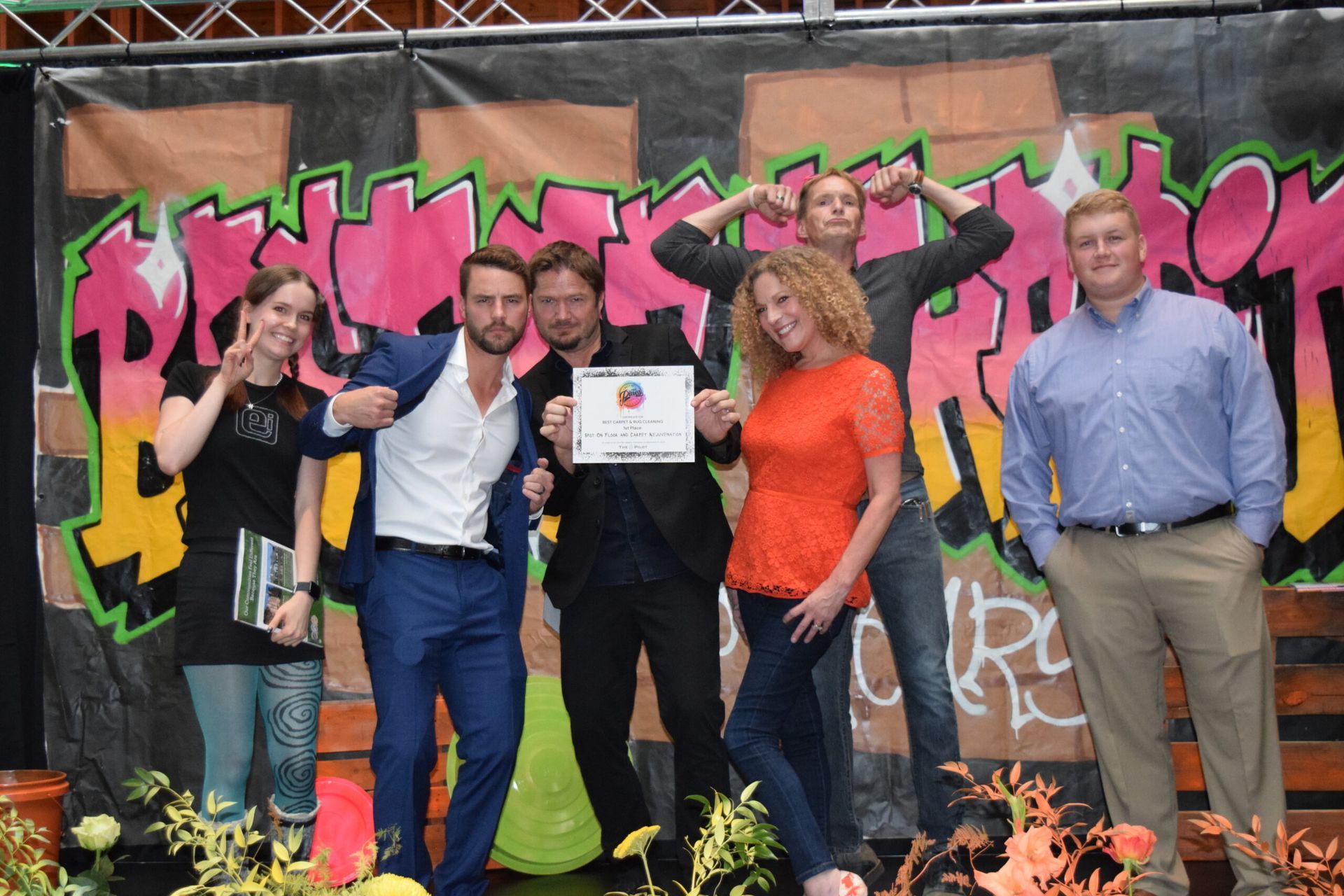A group of people are posing for a picture in front of a graffiti wall.