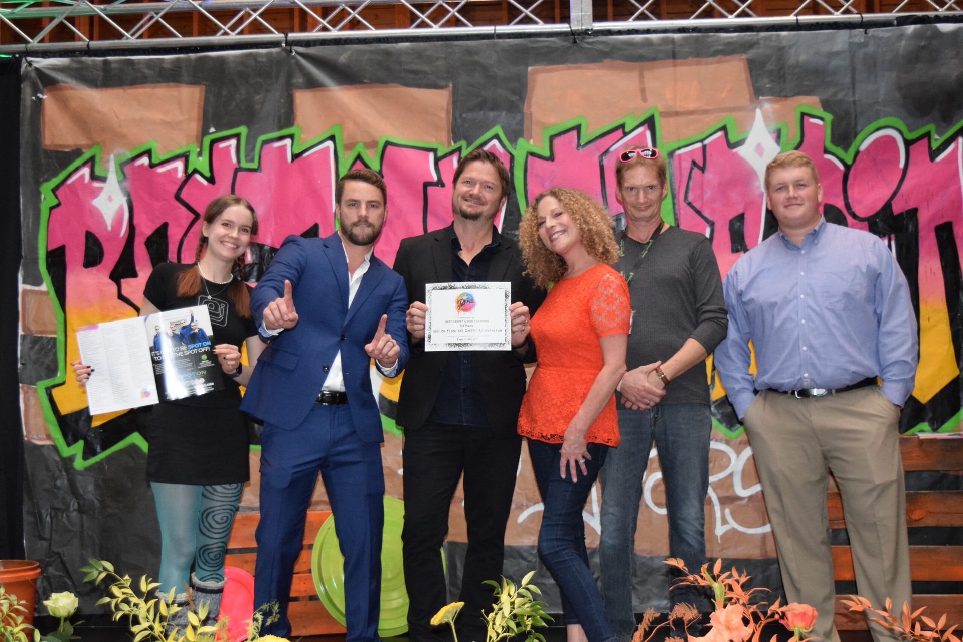 A group of people are posing for a picture in front of a graffiti wall.