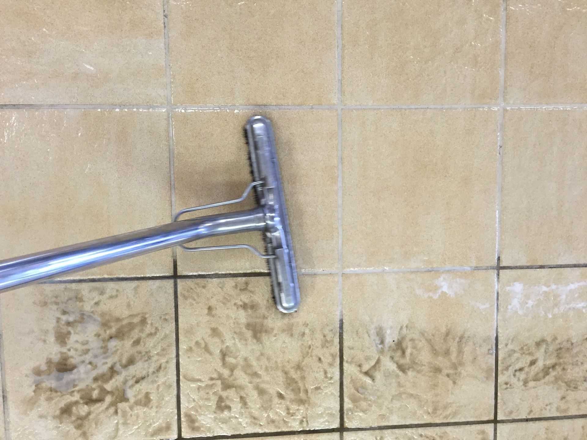 A vacuum cleaner is cleaning a dirty tile floor.