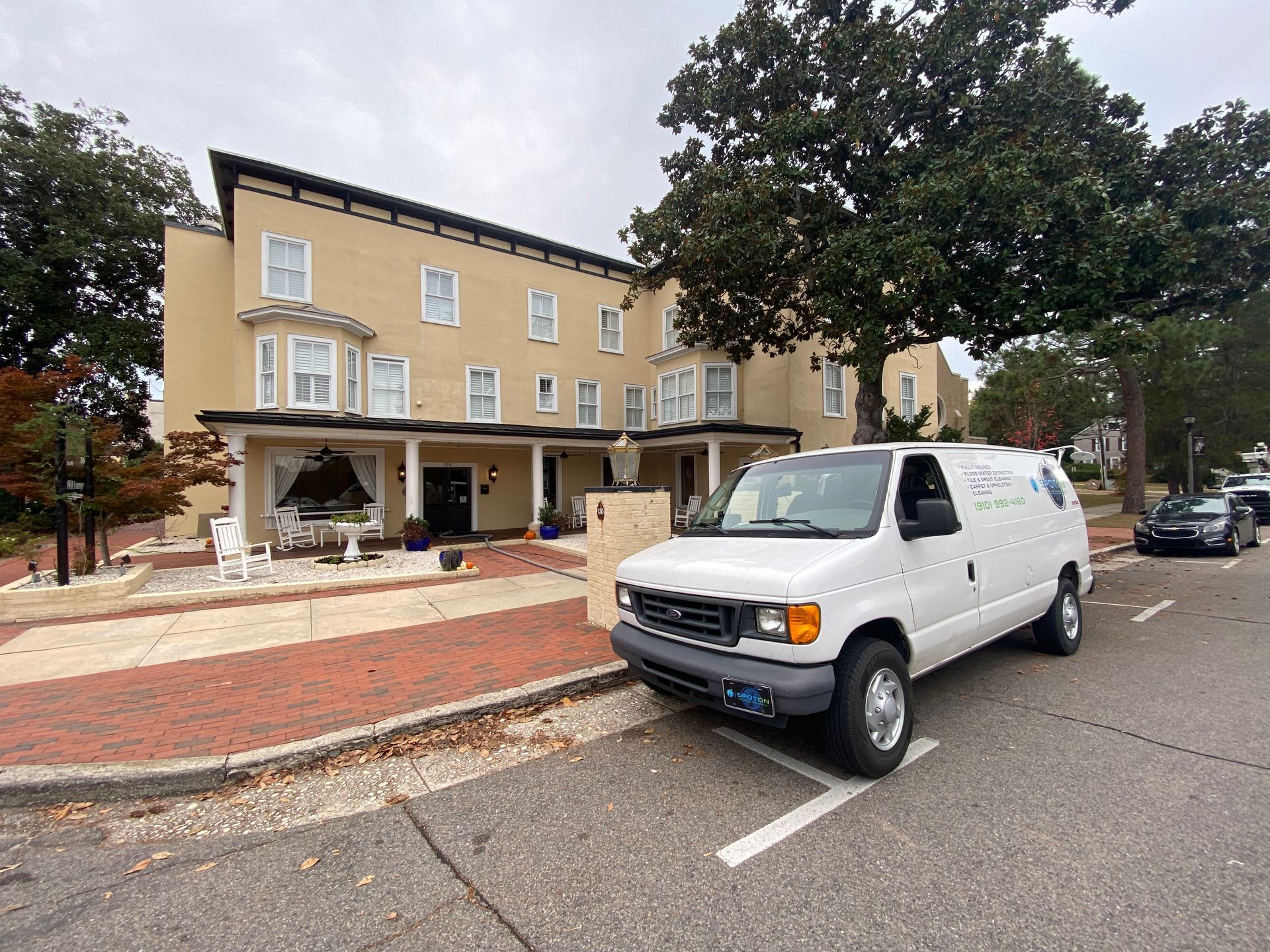 A white van is parked in front of a large building.