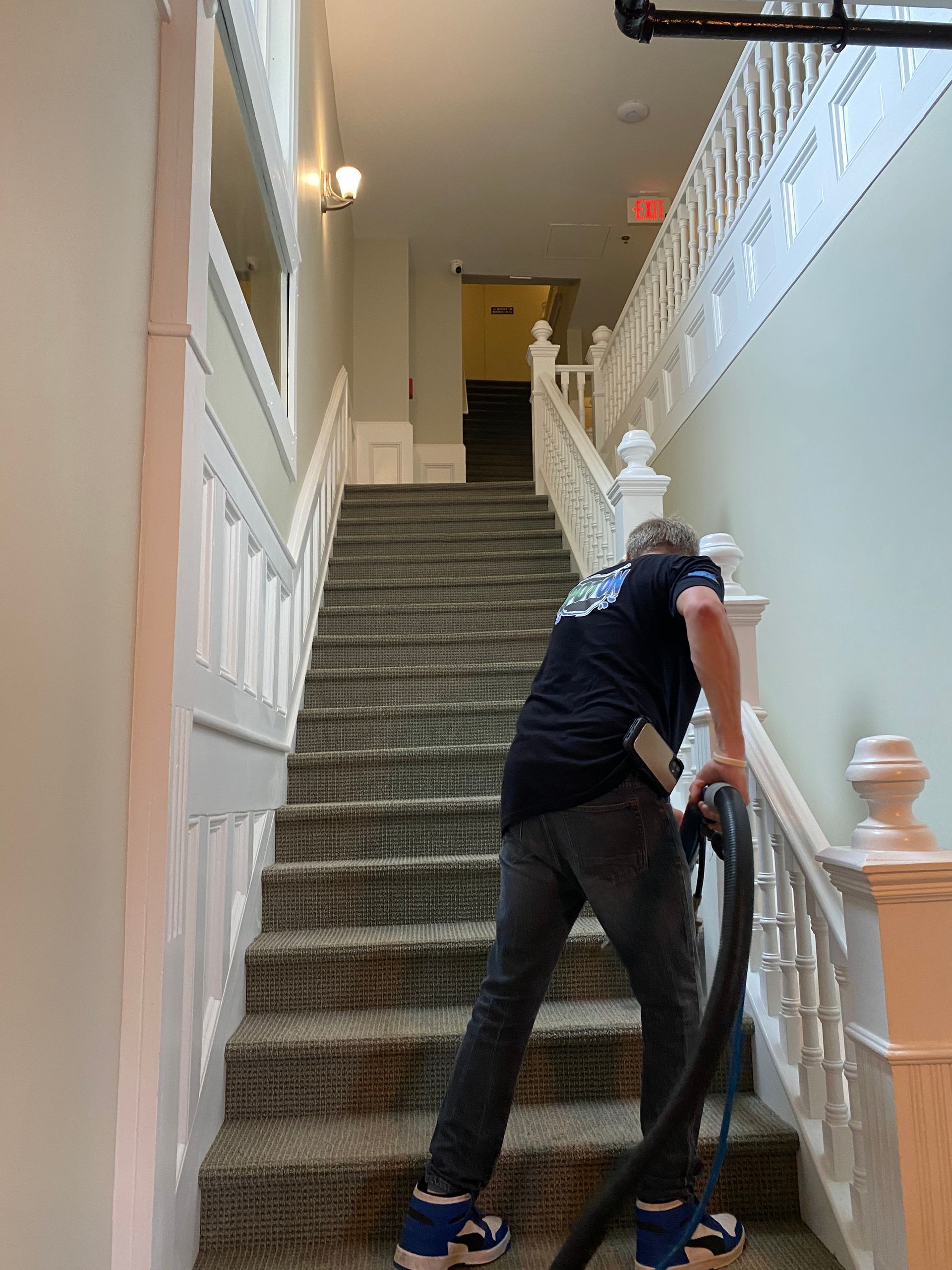 A man is using a vacuum cleaner to clean the stairs.