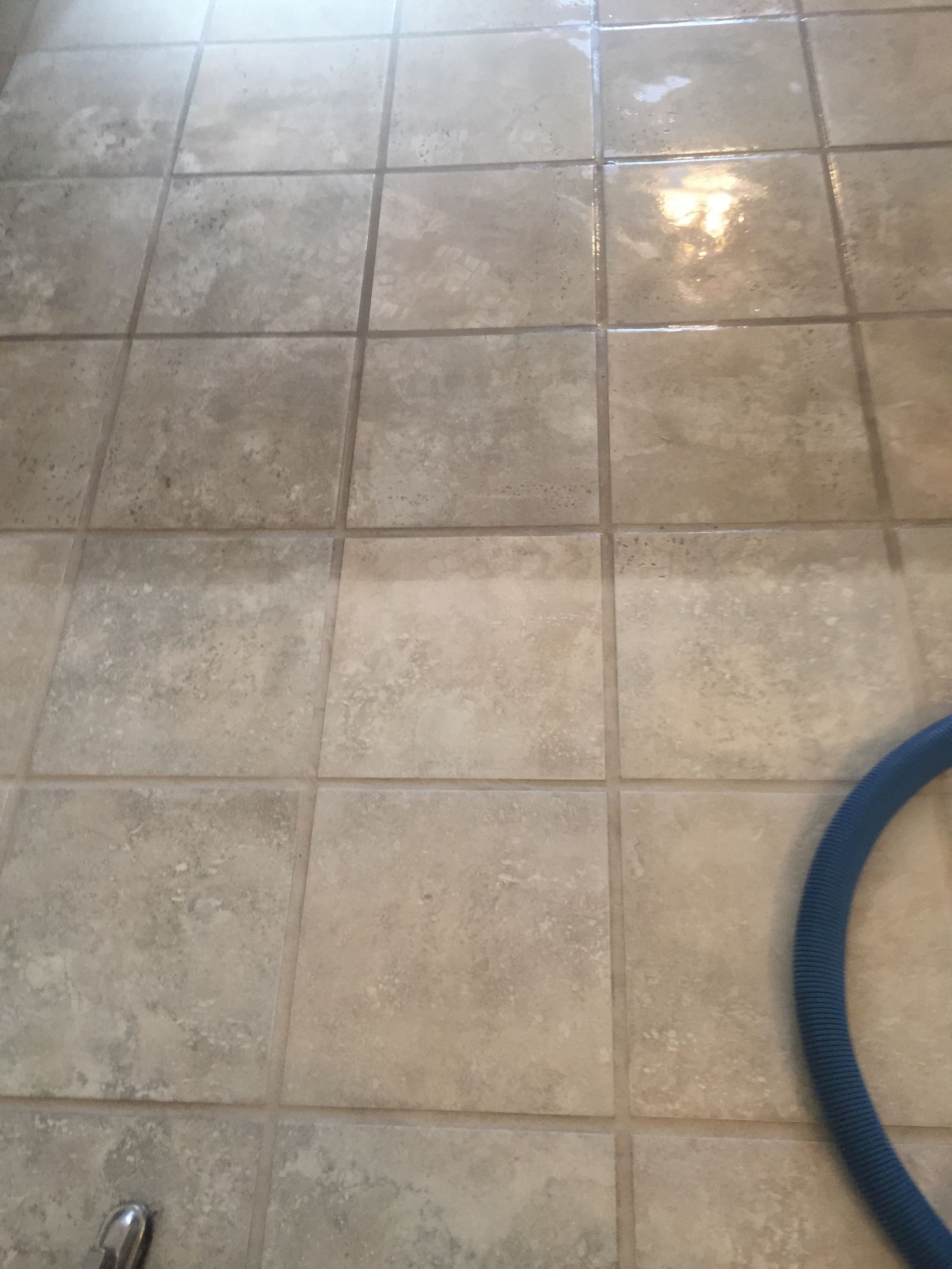 A tile floor is being cleaned with a vacuum cleaner.