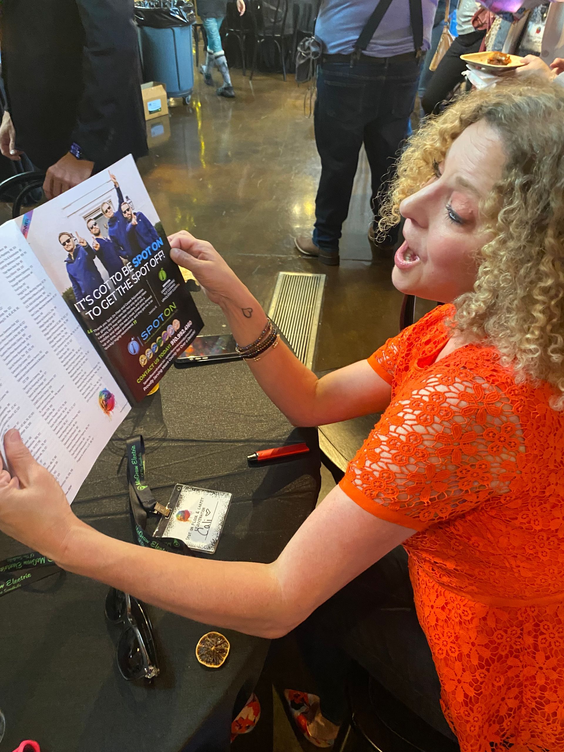 A woman in an orange top is reading a magazine