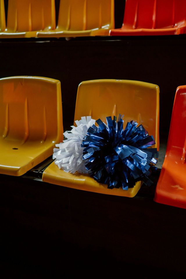 Blue and white pom-poms on yellow stadium seats, with red seats nearby