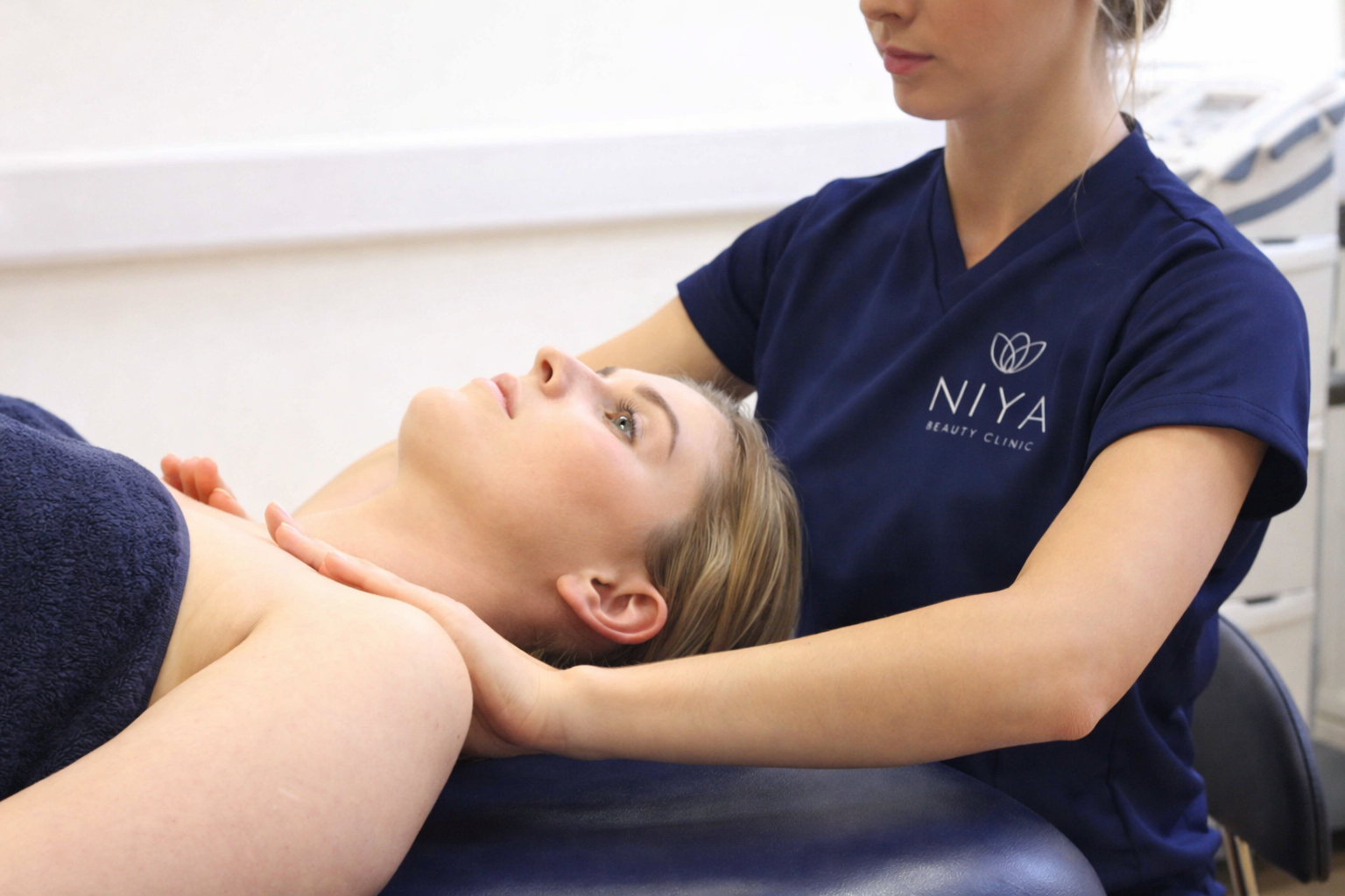 Woman receiving neck massage from a therapist in a medical setting.