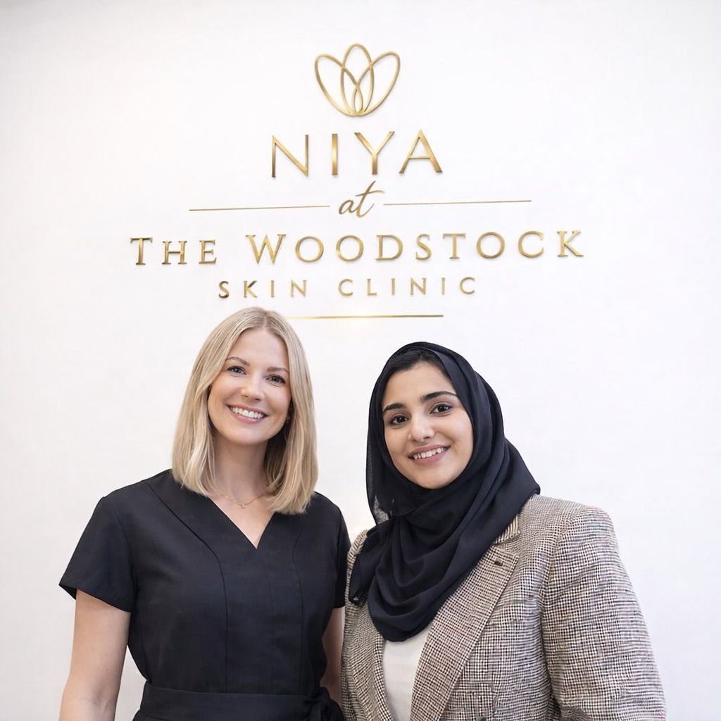Woman with freckles, damp skin, wrapped in a white towel, looking at the viewer.