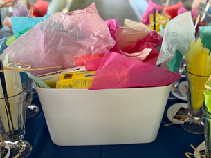 A white basket filled with tissue paper and other items on a table.