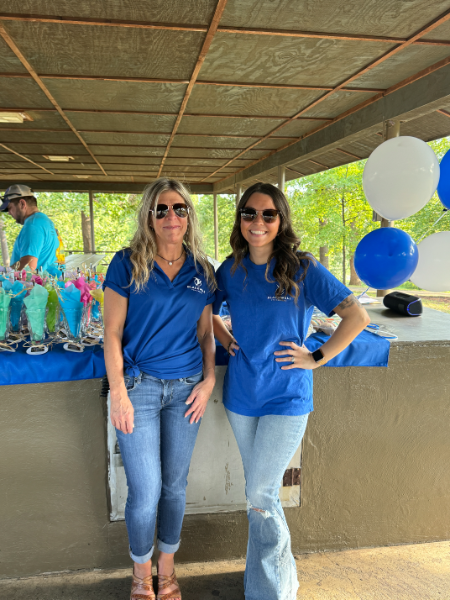Two women wearing blue shirts are standing next to each other