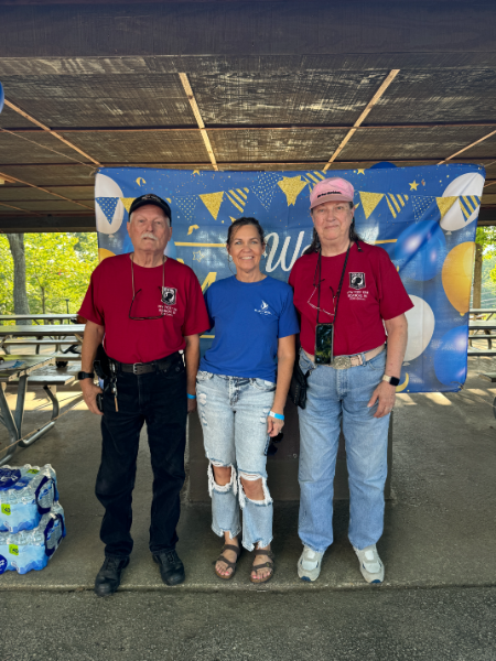 Three people are posing for a picture in front of a sign that says welcome