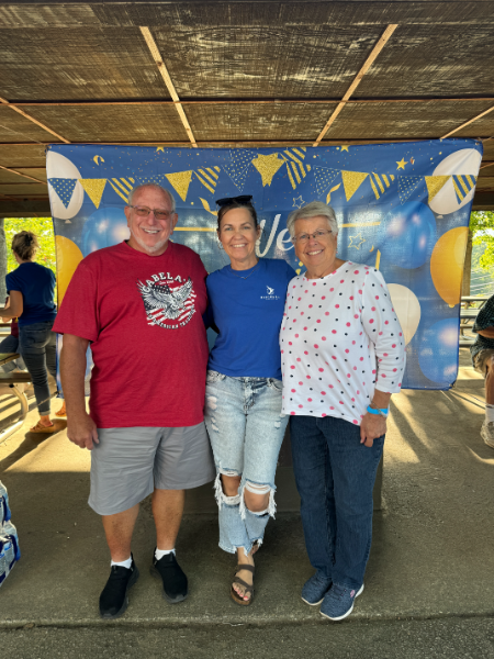 Three people posing for a picture in front of a sign that says welcome