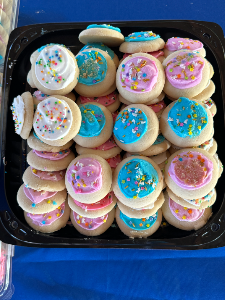 A tray of cookies with pink and blue frosting and sprinkles