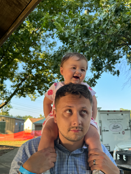 A man is carrying a baby on his shoulders.