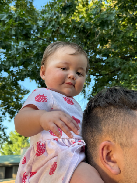 A man is carrying a baby on his shoulders