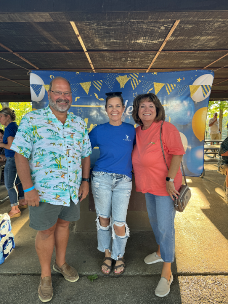 A man and two women are posing for a picture under a tent.