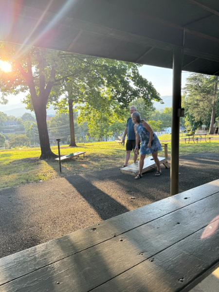A group of people are playing cornhole in a park.