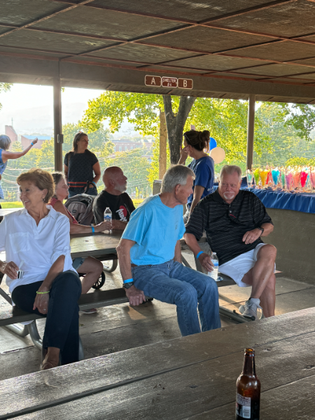A group of people are sitting at picnic tables in a pavilion.