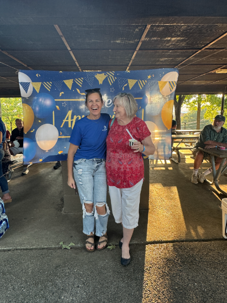 Two women are posing for a picture in front of a banner that says annie