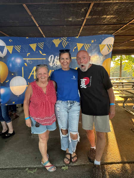 Three people posing for a picture in front of a banner that says 26
