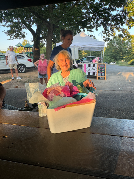 A woman is sitting at a table with a basket of clothes on it.