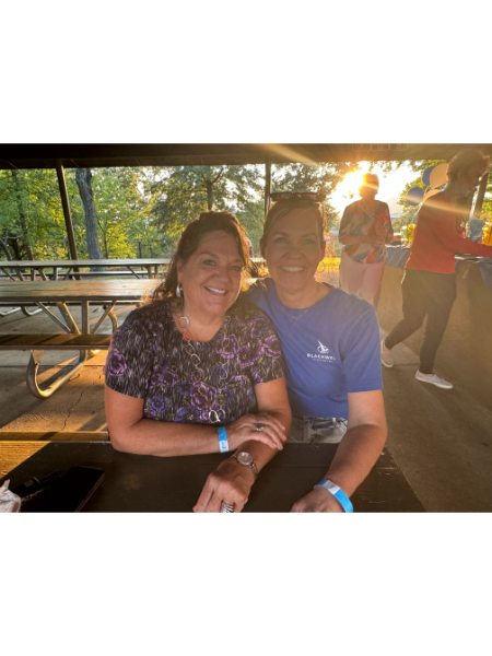 A man and a woman are posing for a picture while sitting at a picnic table.